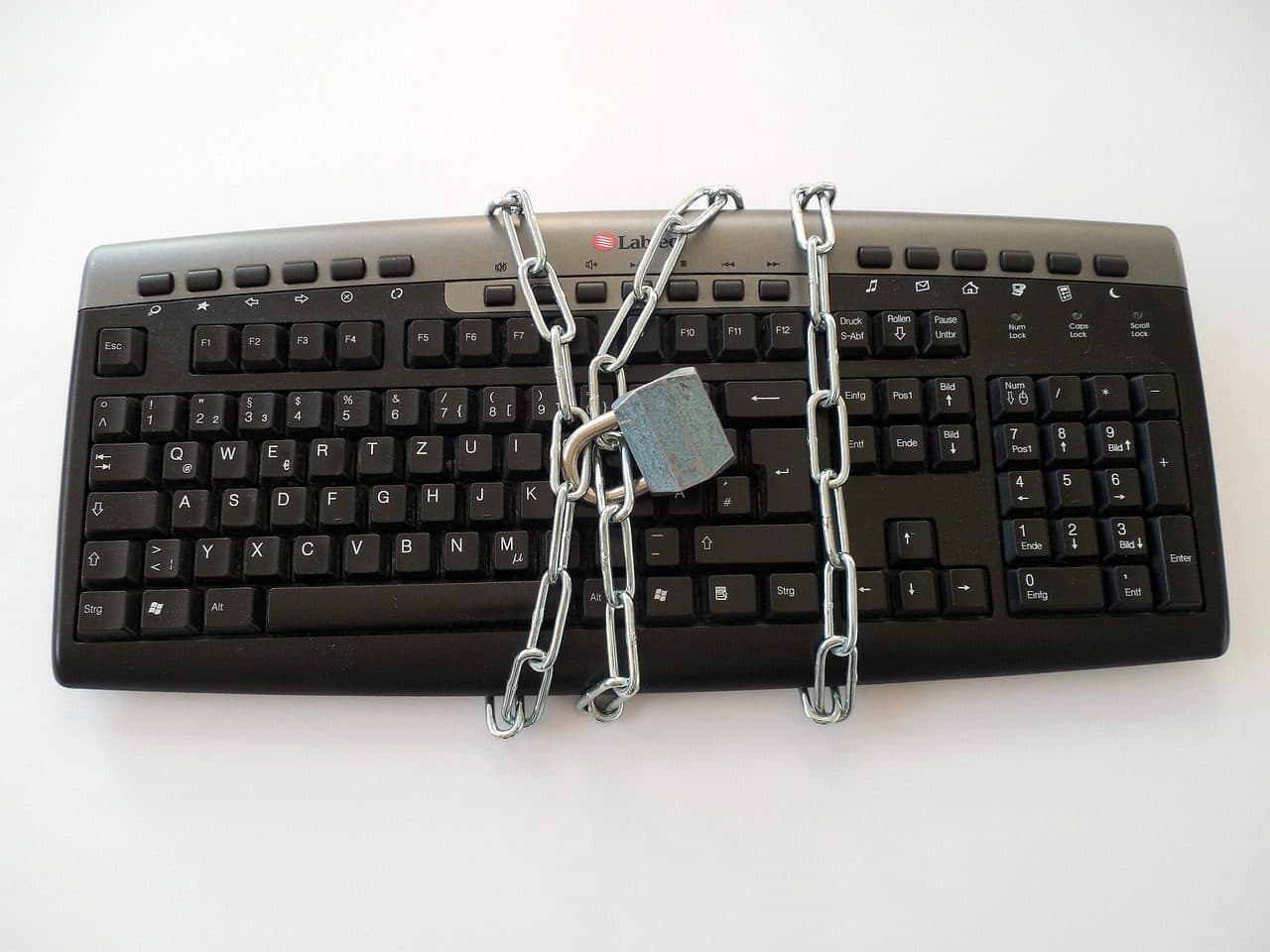 A metal padlock and chain resting on a laptop keyboard