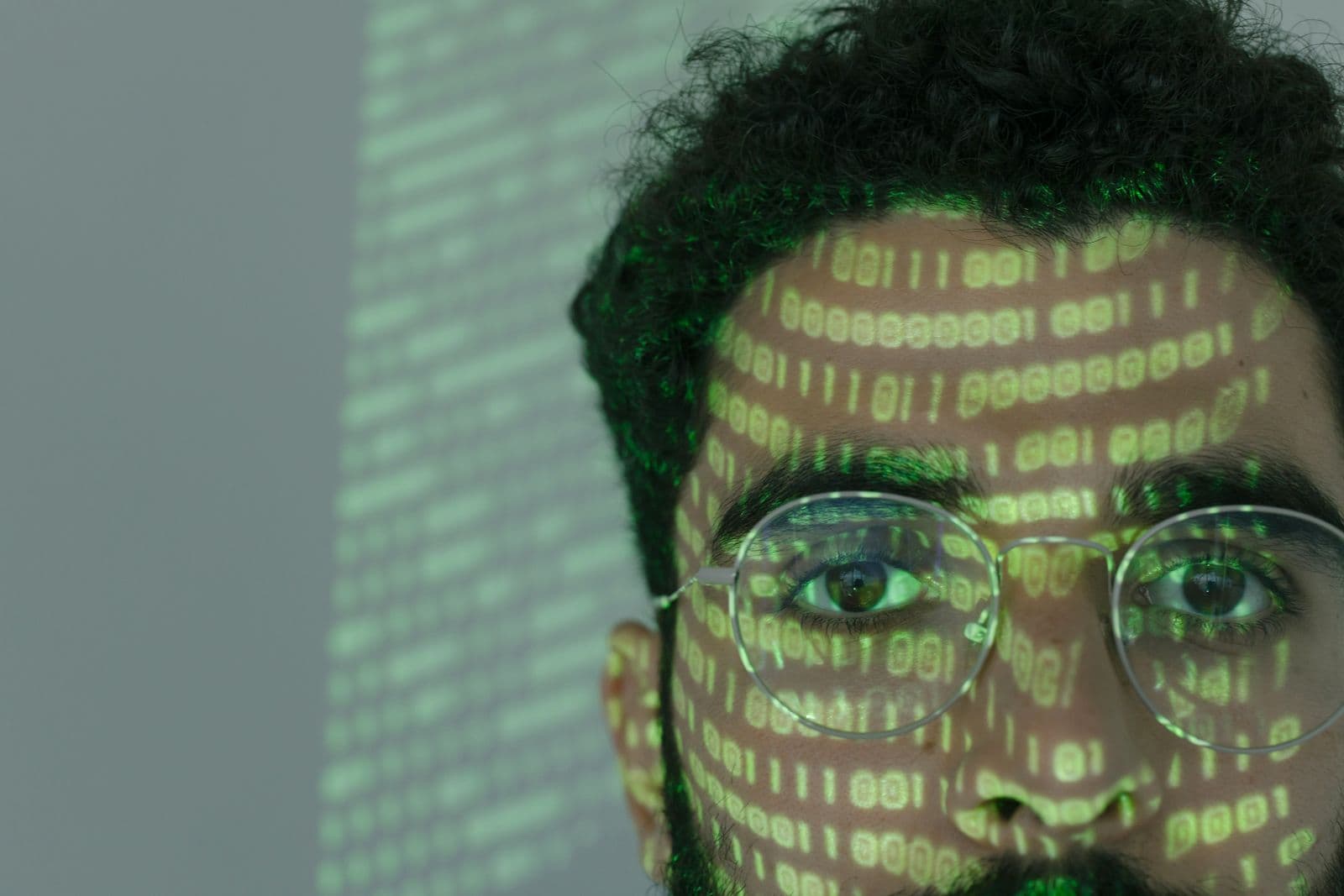 A man's face with lines of binary code projected onto it