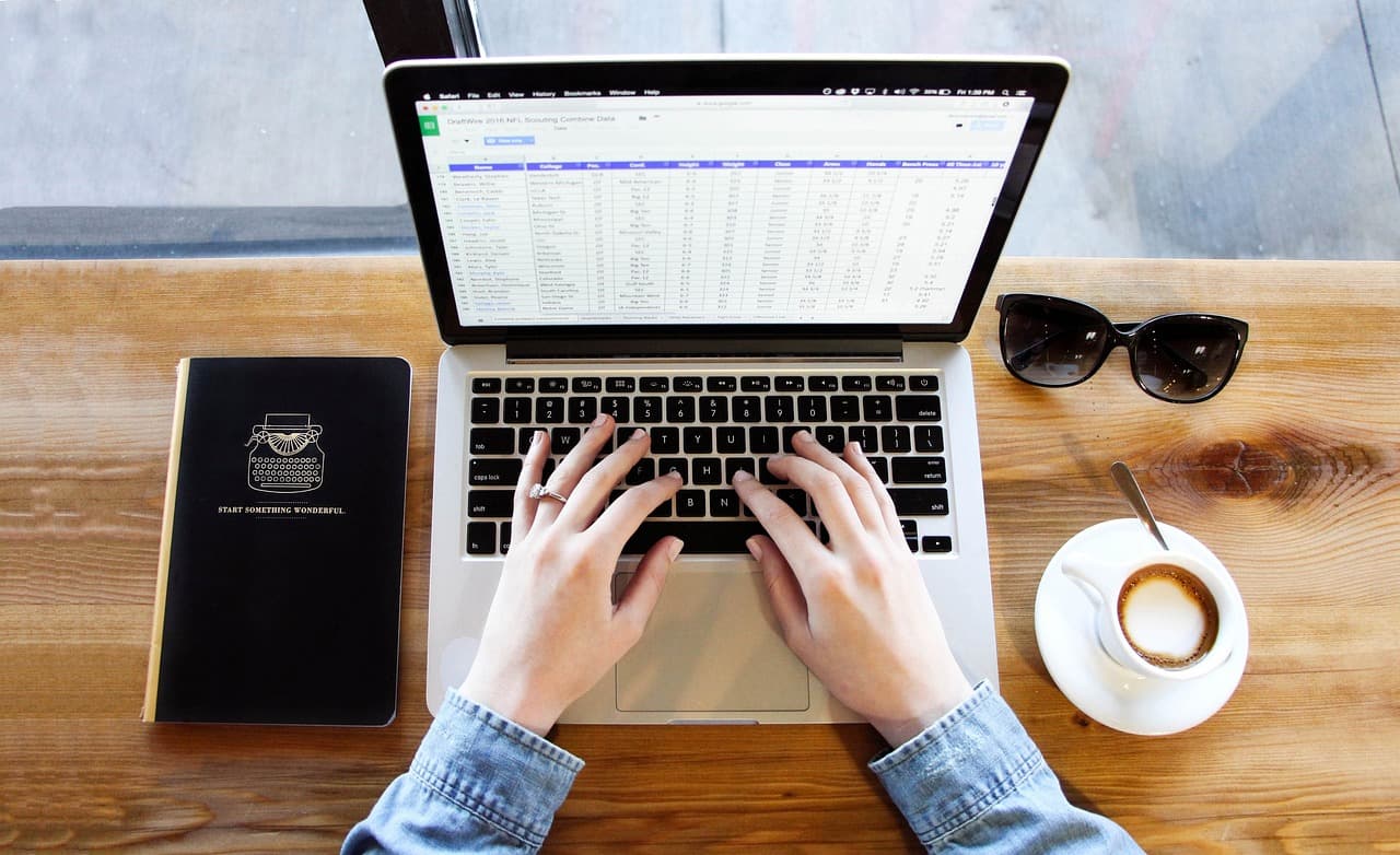 Trabajando en un portátil en un escritorio con un café, el tipo de configuración en la que funciona un gestor de contraseñas