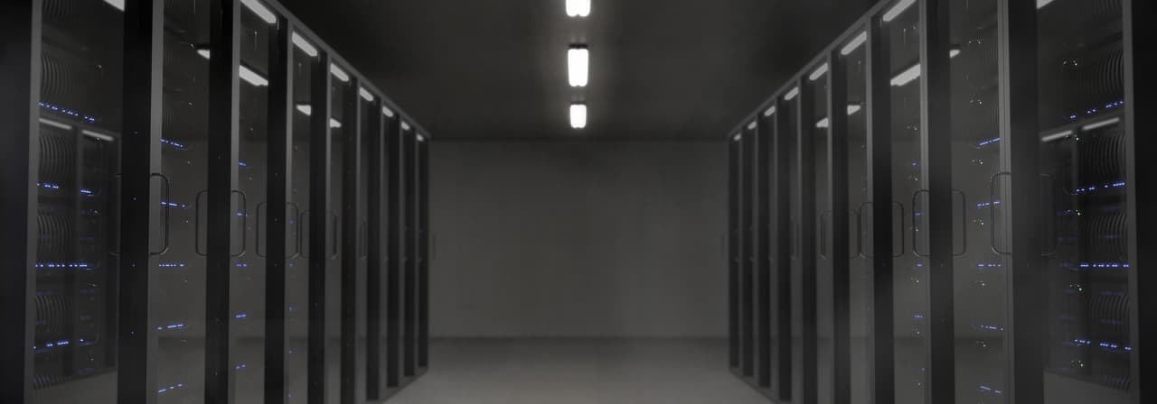 Ein dunkler Serverraum mit Gerätereihen, beleuchtet von kleinen LEDs