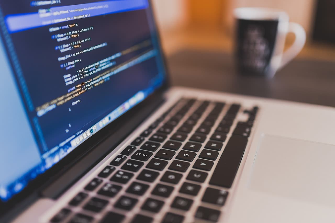 A laptop showing code on a developer's desk next to a coffee mug